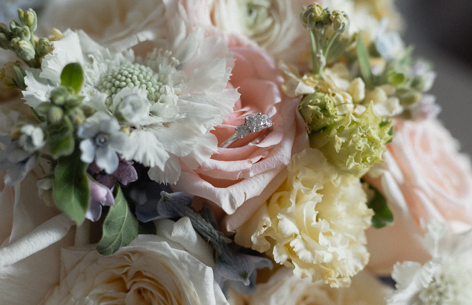 Diamond engagement ring nestled in a blush and cream bouquet