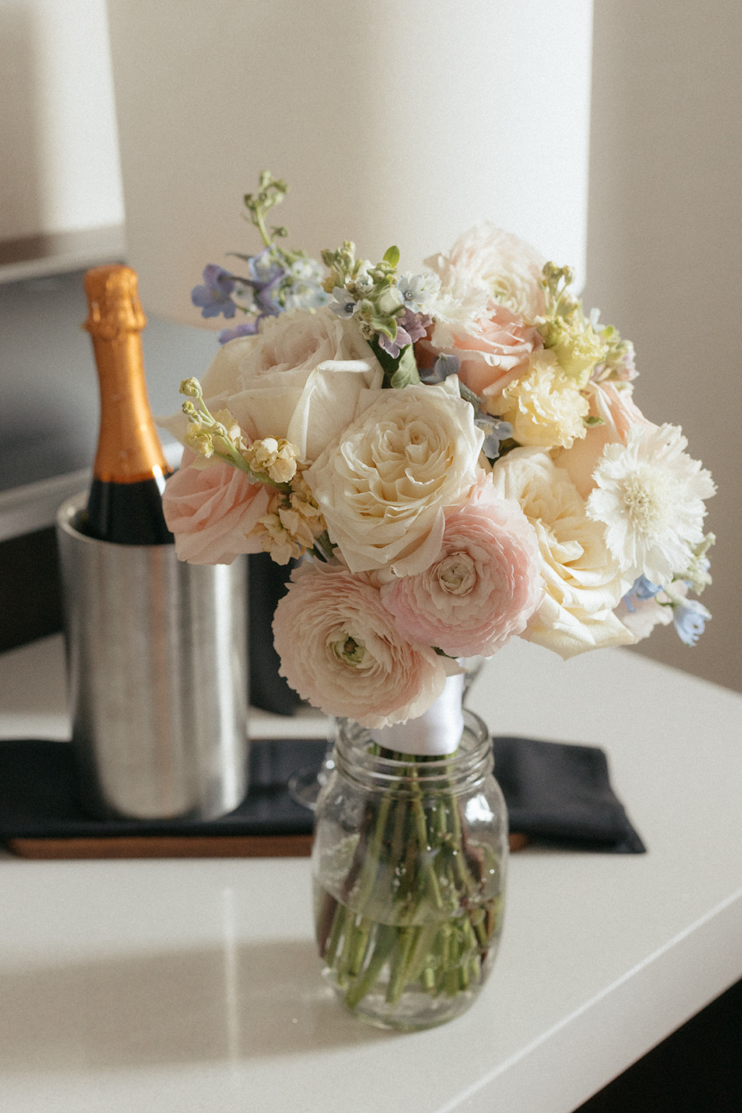 Bridal bouquet in a mason jar beside chilled champagne